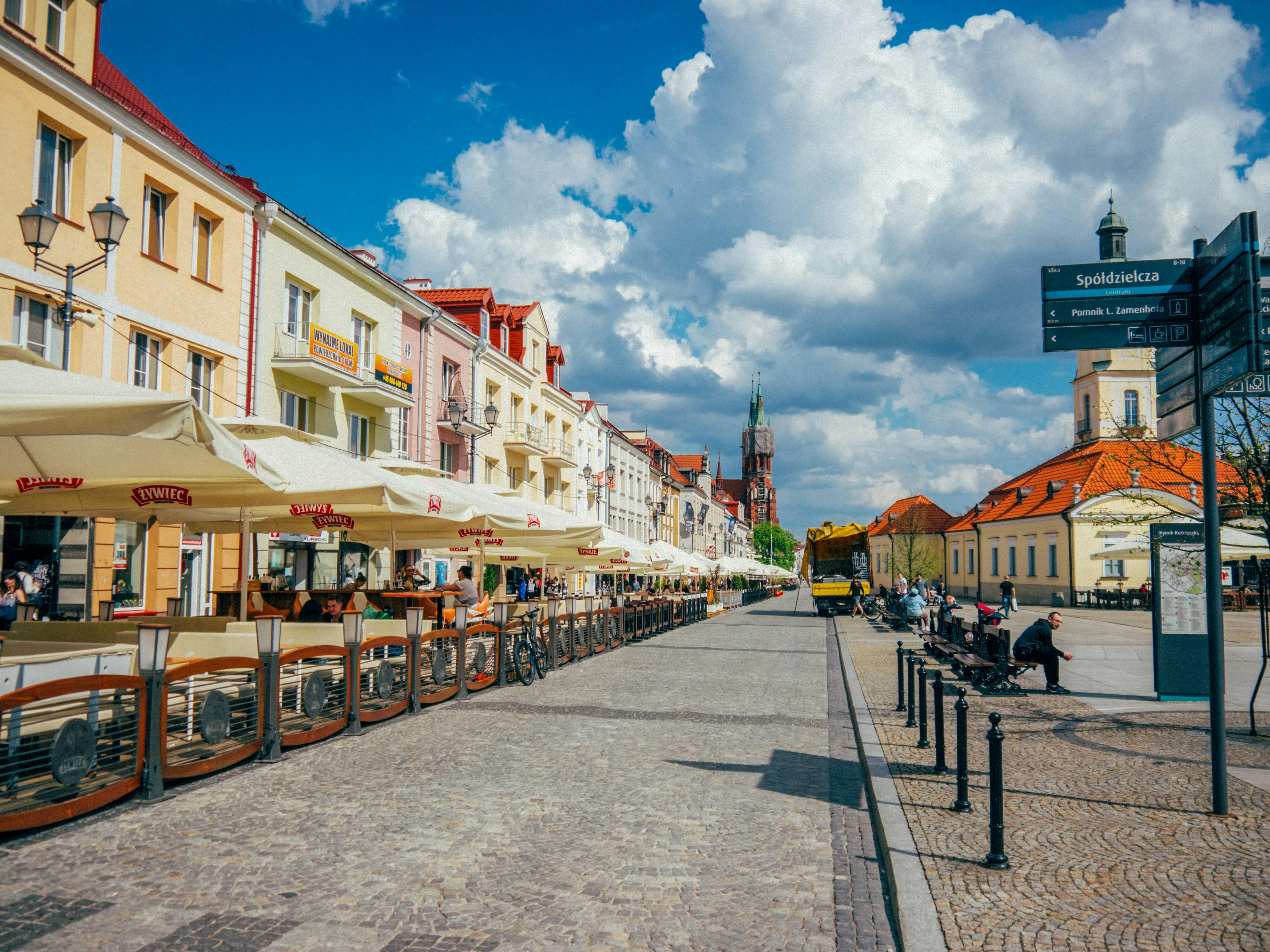 Stare miasto w Białymstoku - mieście istotnym dla spedycji. Uliczka Starego Miasta w Białymstoku, widać parasole i kamienice, jest słonecznie.
